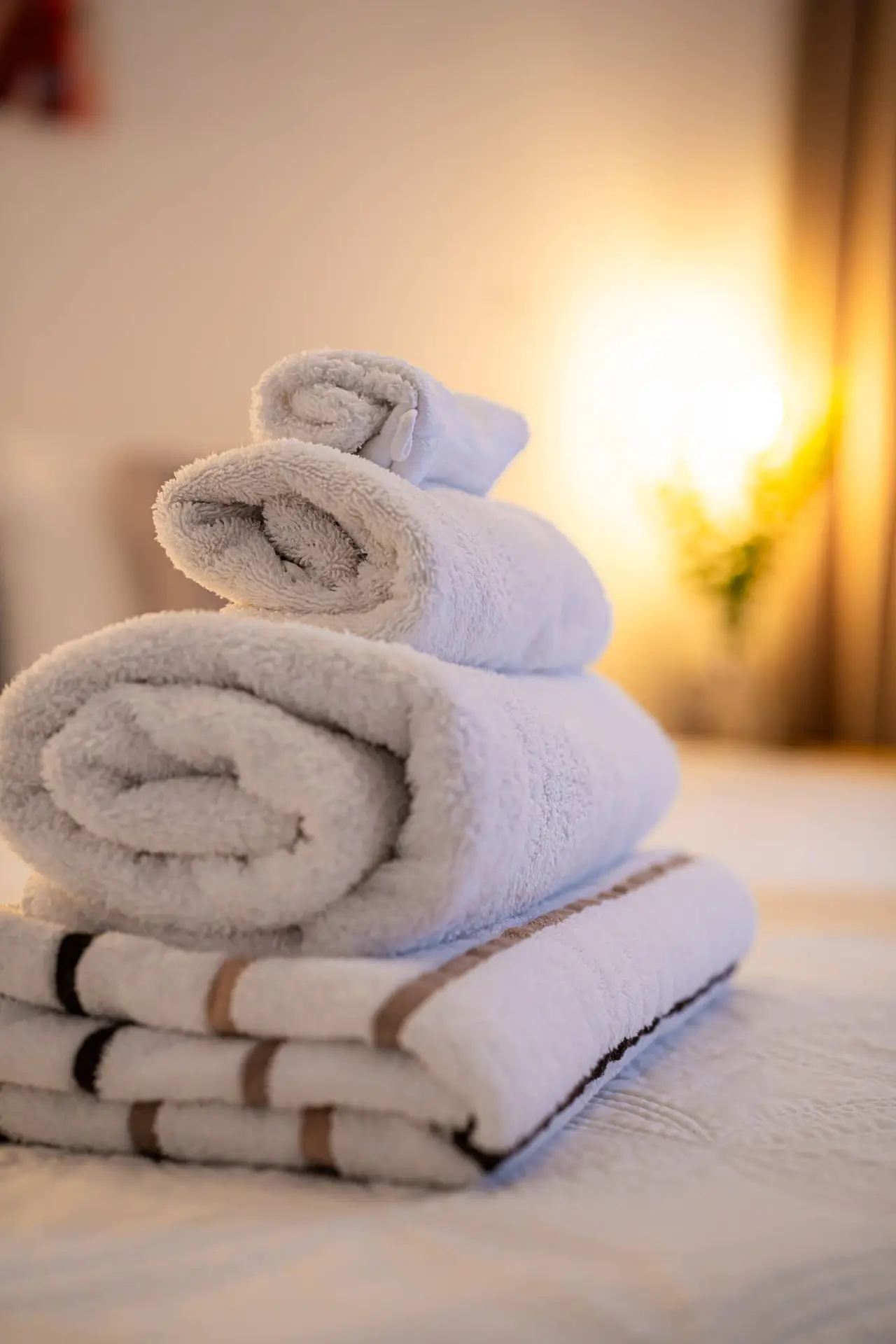 A stack of plush, neatly folded towels on a comfortable bed, illuminated by warm lighting, ensuring a welcoming and relaxing stay in Curaçao.