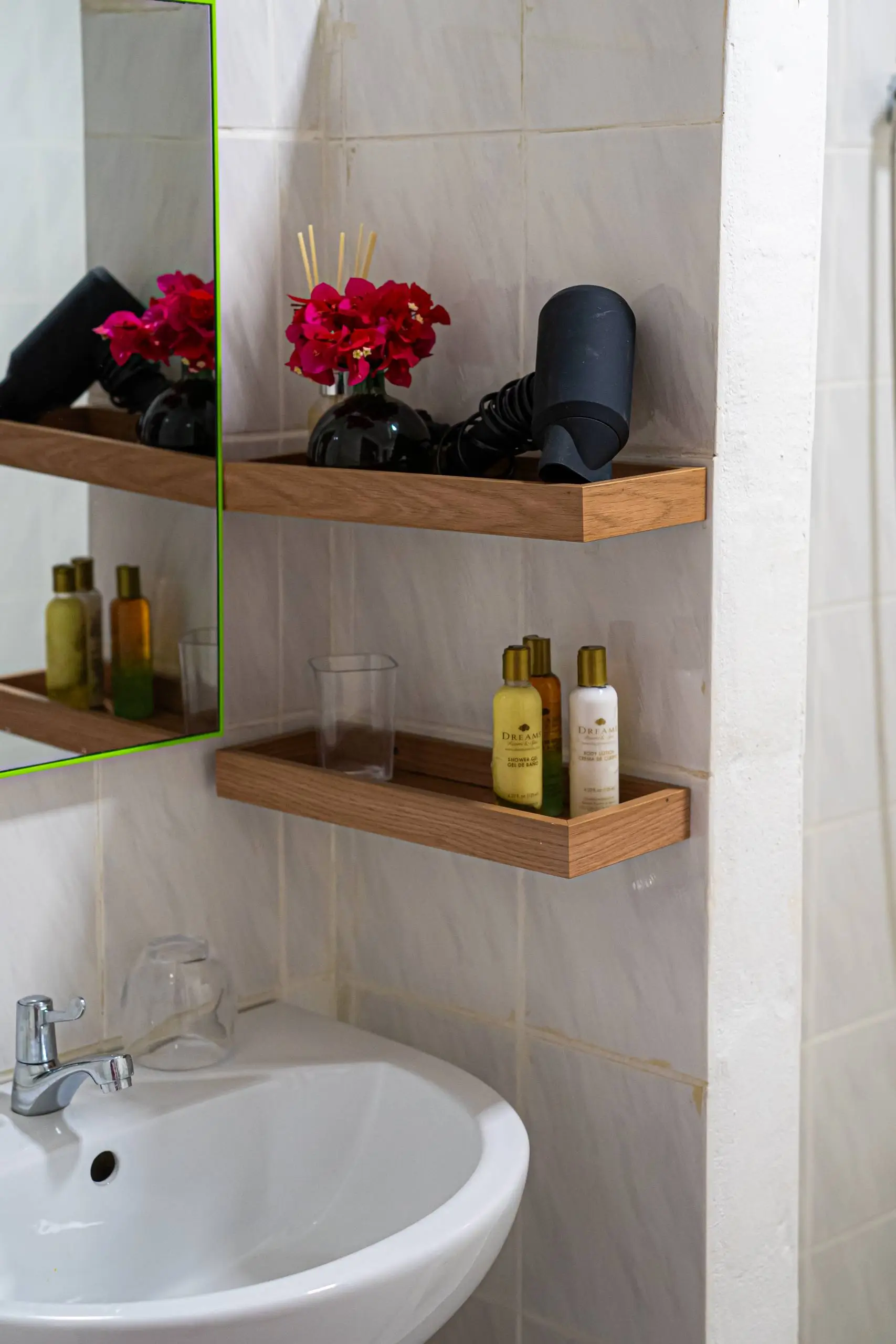 A stylish bathroom shelf with luxury toiletries, a hairdryer, and decorative flowers, providing guests with essential comforts in a well-appointed space.